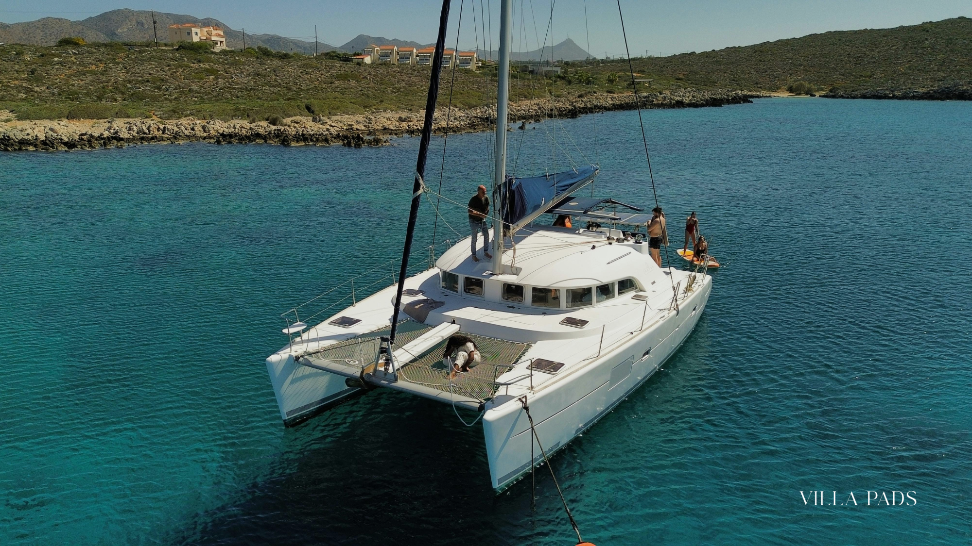 Private Catamaran Anchored In A Crystal Clear Secluded Cove Off The Mykonos Coastline